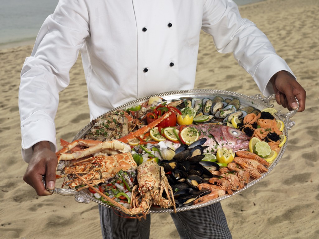 Chef holding a platter of fresh seafood istock